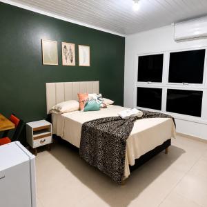 a bedroom with a bed and a green wall at Hotel Presidente Ibirubá in Ibirubá +66 photos
