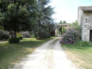 a dirt road next to a house with a tree and flowers at Gite de la Maison Noble in Champagné-le-Sec
