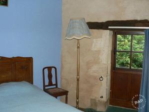 a bedroom with a bed and a lamp and a window at Gite de la Maison Noble in Champagné-le-Sec