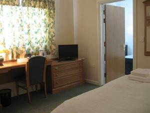 a bedroom with a desk with a computer and a bed at Hazelwood Guest House in Bridgend