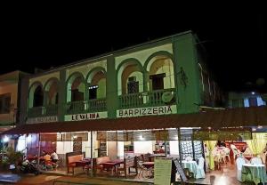 a green building with tables and chairs in front of it at Le Valiha Hotel in Antsiranana