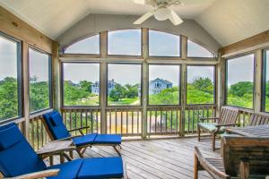 a screened in porch with blue chairs and windows at 2433 - Bella Bay in Duck