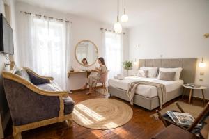 a woman sitting at a desk in a bedroom at Apeiron Acropolis Suites by HC in Athens