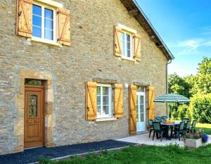 a stone house with a table and an umbrella at La ferme de la fontaine in Douzy