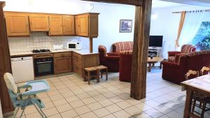a kitchen with wooden cabinets and a living room at La ferme de la fontaine in Douzy
