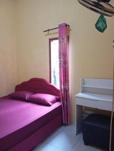 a bedroom with a bed with purple sheets and a window at Thian Homestay in Batukaras