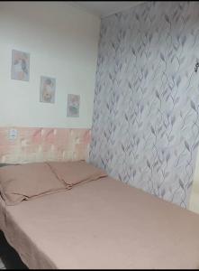 a bedroom with a white bed with a gray wall at Suítes em Parintins in Parintins