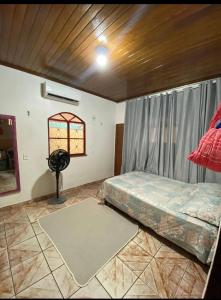 a bedroom with a bed and a window and a fan at Suítes em Parintins in Parintins