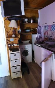 a kitchen with a washing machine and a table with a lamp at Le Chalet De Pierre Sèche in Chaumard