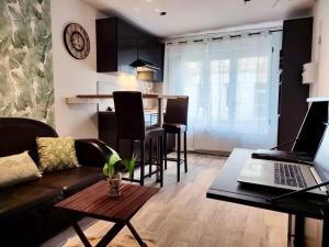 a living room with a couch and a table with a laptop at L'escale Niortaise - Centre-ville - 10mn Gare - WIFI - Netflix in Niort