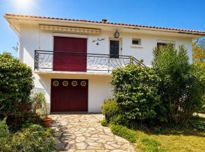 a white house with a red door and a balcony at maison moderne en face de la mer in Arès