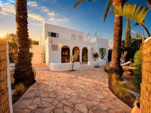 a white house with palm trees in front of it at La IBICENCA & JACUZZI by XimoApartments in Oliva