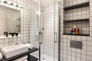 a white tiled bathroom with a sink and a shower at RockyPop Chamonix - Les Houches in Les Houches