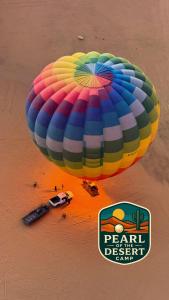 a large colorful parachute on a beach with a car at Pearl of the desert camp in Wadi Rum