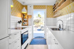 a kitchen with white cabinets and a door leading to a patio at 16669-Farevejle-Alfestien-52 in Fårevejle +18 photos