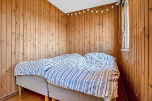 a bed in a room with a wooden wall at 16669-Farevejle-Alfestien-52 in Fårevejle