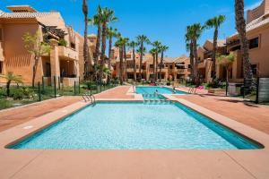 a pool at a resort with palm trees and buildings at Ribera Beach in Los Alcázares