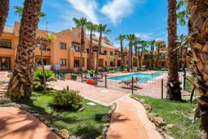 a resort with a swimming pool and palm trees at Ribera Beach in Los Alcázares