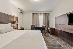 a hotel room with a large bed and a desk at Slaviero Hotel Curitiba Centro in Curitiba