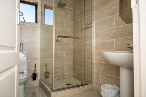 a bathroom with a shower with a toilet and a sink at Sycamon Suites in Jwaneng