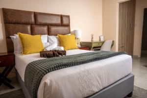a bedroom with a large bed with yellow pillows at Sycamon Suites in Jwaneng