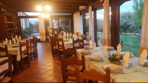 a dining room with tables and chairs and windows at Agriturismo nuraghe Putzu Canu in Perfugas