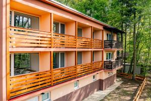 an orange building with wooden balconies and trees at Penzion Kopaninky in Bítov +11 photos