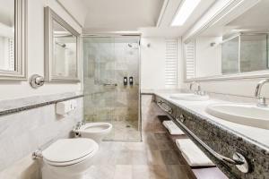 a bathroom with a toilet and two sinks and a shower at Slaviero Hotel Curitiba Centro in Curitiba