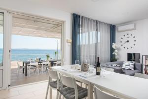 a dining room and living room with a view of the ocean at Villa Victoris Beachfront Luxury Villa with Heated Spa Pool Podstrana in Podstrana