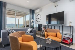 a living room with a couch and chairs and a tv at Villa Victoris Beachfront Luxury Villa with Heated Spa Pool Podstrana in Podstrana
