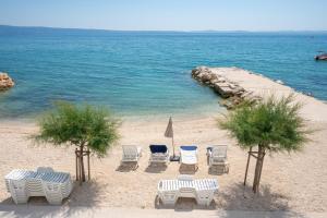 a group of chairs and tables on a beach at Villa Victoris Beachfront Luxury Villa with Heated Spa Pool Podstrana in Podstrana