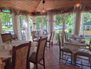 a dining room with tables and chairs and windows at Hotell Tussilago i Essunga in Nossebro