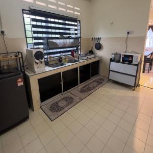 a kitchen with a counter with a sink and a window at Yasmeen pool cottage in Temerloh