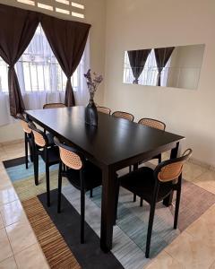 a black dining room table with chairs and a vase on it at Yasmeen pool cottage in Temerloh