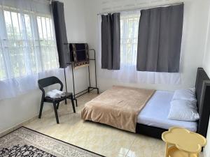 a bedroom with a bed and a chair and windows at Yasmeen pool cottage in Temerloh