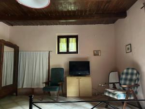 a living room with two chairs and a television at Palazzo giallo, appartamento nel centro storico nel cuore del Pollino in Morano Calabro