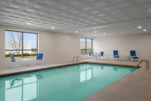 a large swimming pool with blue chairs and a table at Garner Hotel Brockton - Boston by IHG in Brockton