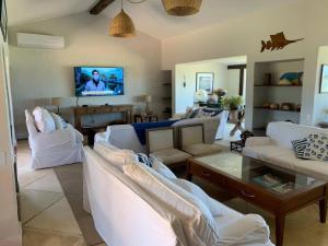 ein Wohnzimmer mit weißen Sofas und einem Fernseher in der Unterkunft Casa do Ventoo in Búzios