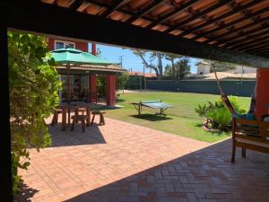 eine Terrasse mit Picknicktischen und einem grünen Sonnenschirm in der Unterkunft Casa do Ventoo in Búzios