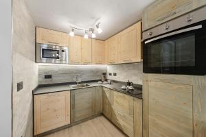 a kitchen with wooden cabinets and a sink and a microwave at Lueur de la Rouja in Champoluc