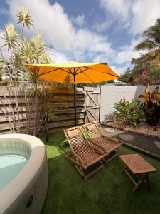 a couple of chairs and an umbrella and a tub at Bungalow la tipik in Saint-François