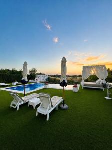 a group of lawn chairs and a swimming pool at Puesta de Sol Doñana Adults Only in Sanlúcar de Barrameda