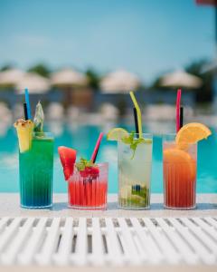 four cocktails on a table next to a pool at Coconut Hotel And Pool in Gevgelija