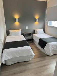 two beds in a small room with two lamps at Hotel República in Villa María