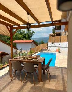 a wooden table and chairs on a patio with a pool at Villa Nature in Kırıkyayla
