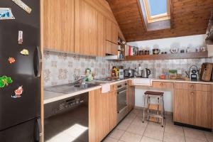 a kitchen with wooden cabinets and a black refrigerator at Charming Alpine Apt with View 5min to Interlaken Ost in Interlaken