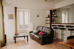 a living room with a leather couch and a table at Le Classique in Saint-Sulpice-le-Guérétois