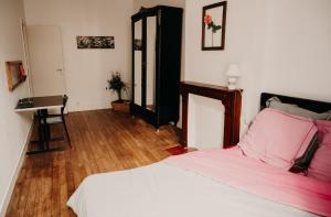 a bedroom with a bed with pink sheets and a desk at Le Classique in Saint-Sulpice-le-Guérétois