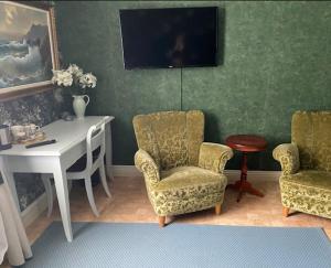 a room with a desk and two chairs and a table at Hotell Tussilago i Essunga in Nossebro