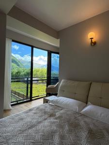 a bedroom with a bed and a large window at Oli Home in Kazbegi